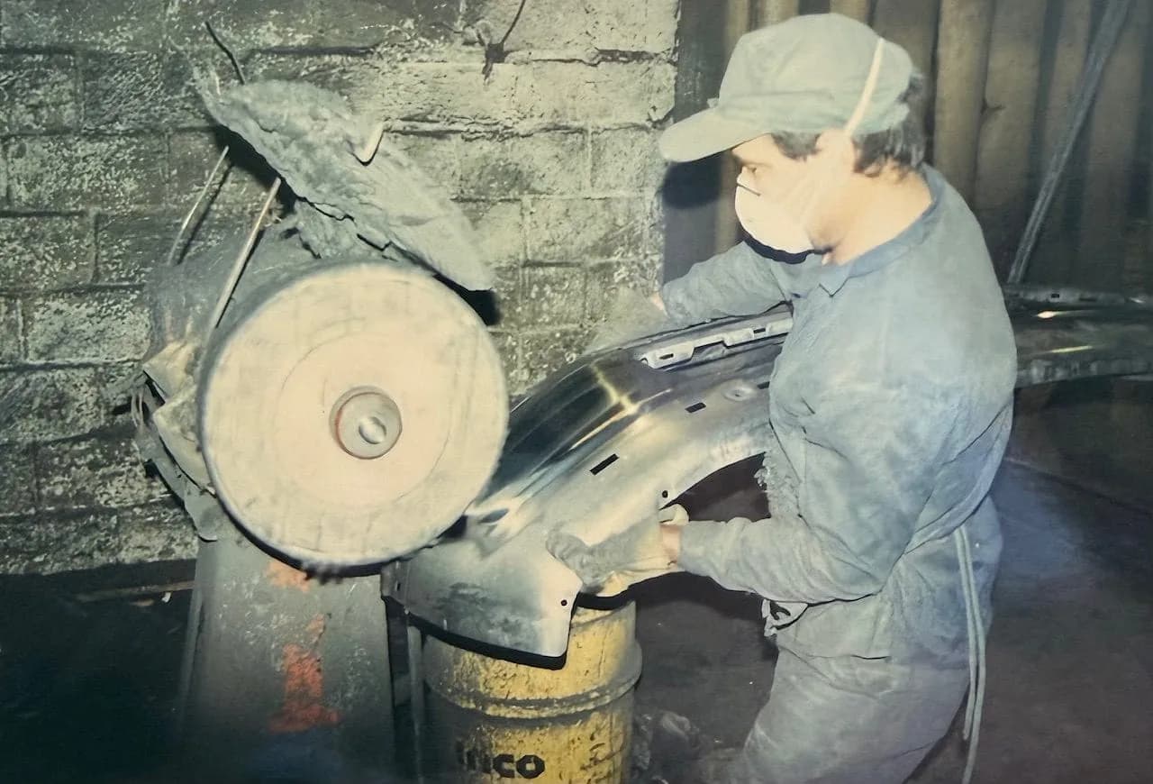 Estañadora craftsman hand-polishing a bumper on the grinding wheel